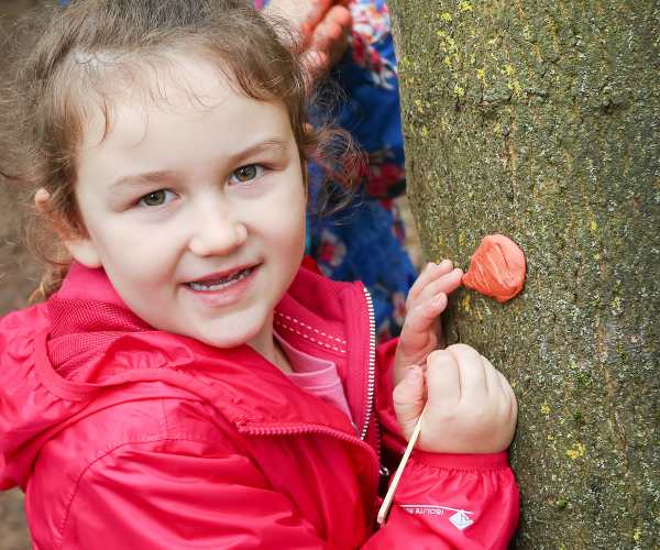 A close-up of a young child having fun with crafts in the woods